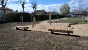 Aire de fitness extérieure avec bancs en bois et barres de traction sur sol en copeaux de bois.